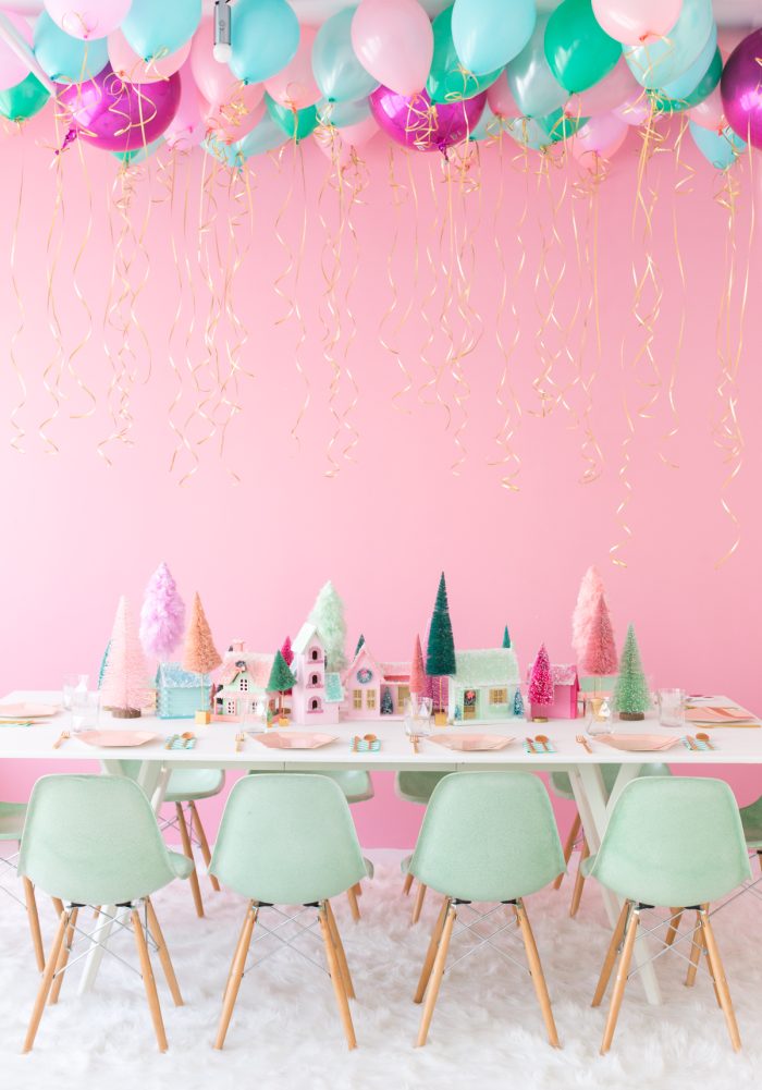 Table set with homemade Christmas village with a pink wall. 
